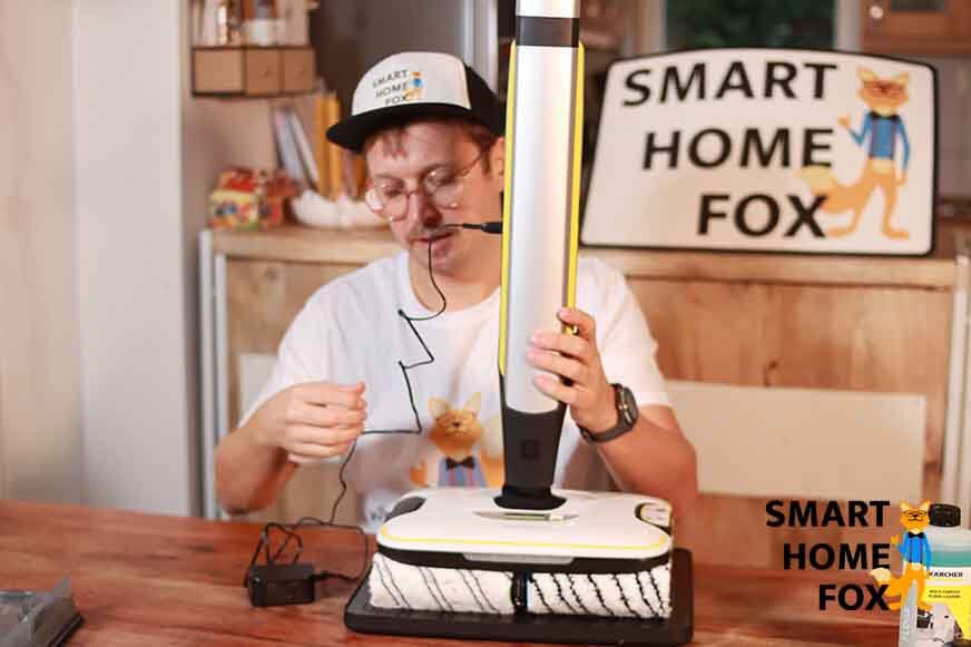 Man sieht, wie der Kärcher FC 7 am Netzteil angeschlossen ist. 